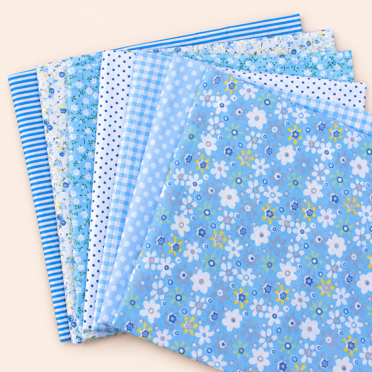 Blue cotton fabric bundle — seven 25 cm squares on cream